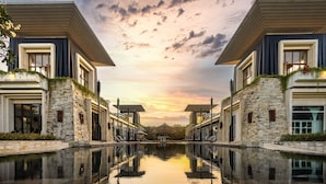 A modern hotel with stone facades, a central courtyard, and a pool reflecting the sky. - The Sakala Resort Bali (Nusa Dua)