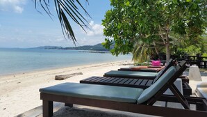 A beachside lounge with wooden benches and a view of the sea. - Grand Manita Beach Resort (Koh Samui)