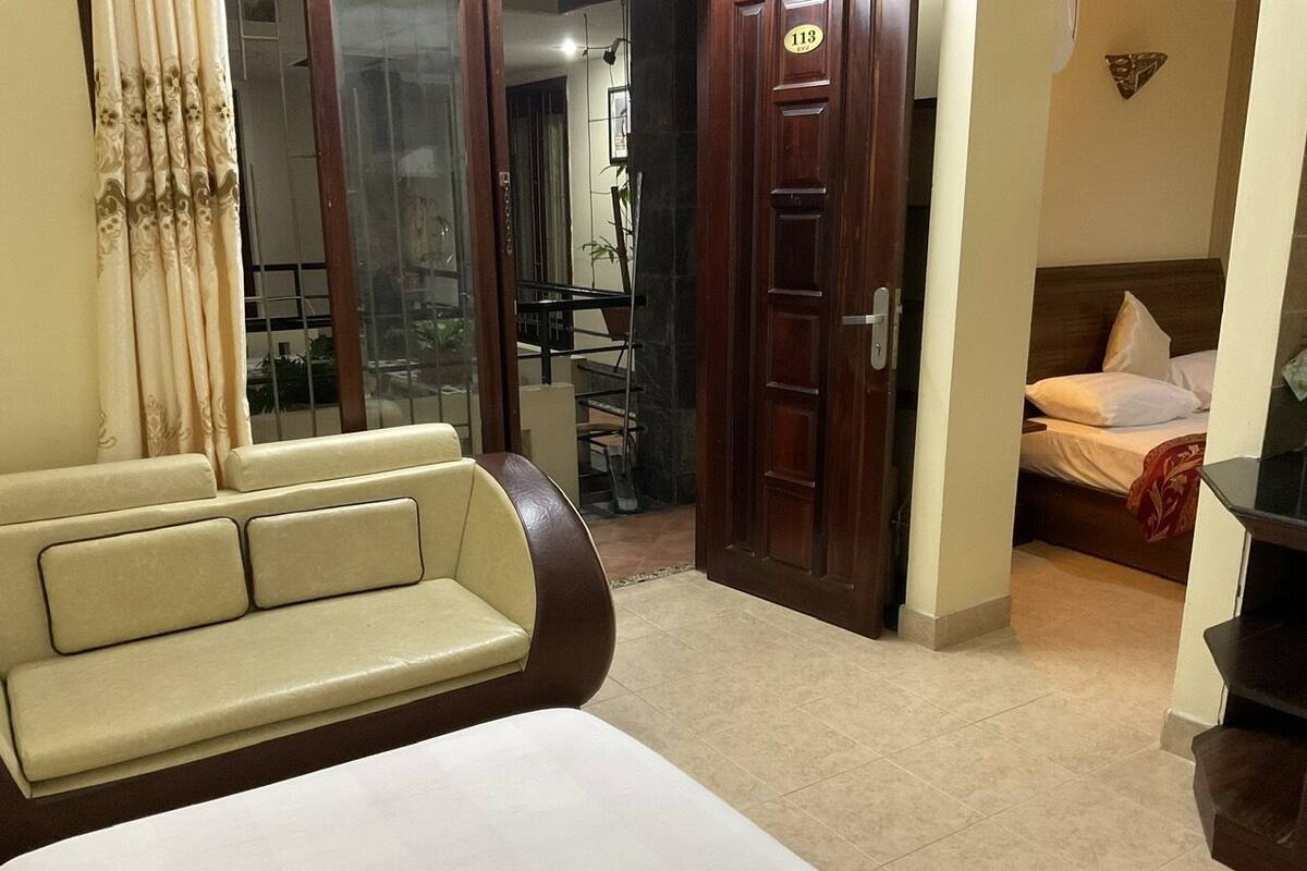 Une chambre d’hôtel avec un lit, un canapé, une porte en bois et une vue sur l’extérieur.