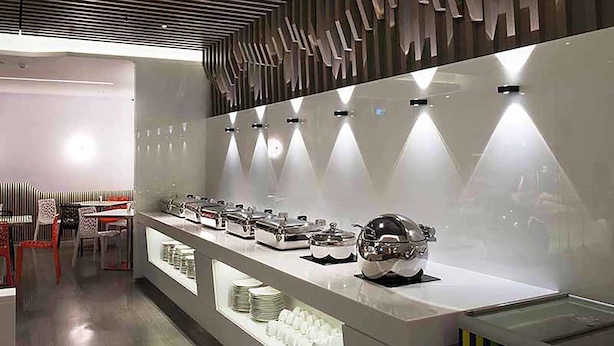 A modern breakfast bar with a sleek design, featuring a series of food dispensers and a decorative wall panel.
