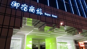 The exterior of the Royal Hotel with a modern facade, illuminated signage, and a prominent entrance.