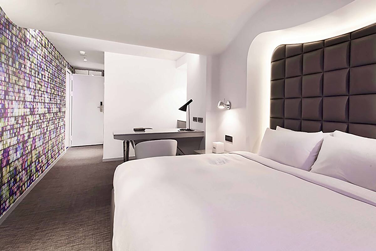 Una habitación de hotel moderna con una cama grande, un escritorio y una silla.