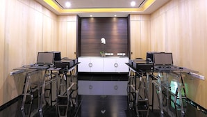 Ein Konferenzraum mit modernem Design, ausgestattet mit einer zentralen Whiteboard-Tafel, zwei Laptops und Glastischen.