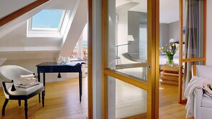 A modern room with a skylight, a glass door leading to a balcony, a white chair, and a small table with books and glasses. - Hôtel de L'Océan (Le Croisic)