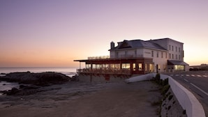 A beachfront hotel with a balcony overlooking the sea, a covered outdoor seating area, and a well-maintained sandy beach. - Hôtel de L'Océan (Le Croisic)