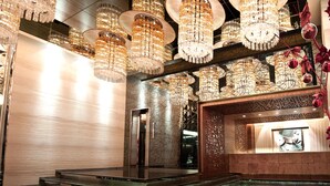 Un hall d’entrée luxueux agrémenté de plusieurs lustres, d’un comptoir de réception et d’éléments décoratifs.