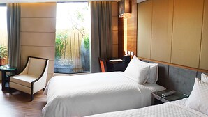 Une chambre d’hôtel avec deux lits, une chaise, un bureau et une fenêtre avec des rideaux.