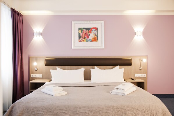Una habitación de hotel con una cama grande, dos mesitas de noche, un cabecero y una obra de arte enmarcada en la pared.