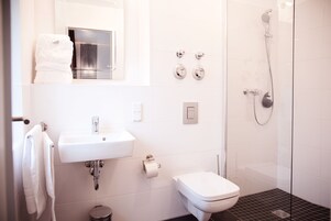 Ein modernes Badezimmer mit Waschbecken, Toilette und einer Duschkabine aus Glas.
