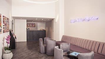 Un área de recepción moderna con un letrero de neón, un mostrador de recepción y arreglos de asientos.