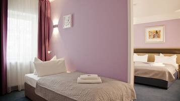 A hotel room with two beds, a large window with sheer curtains, and a wall-mounted light fixture.