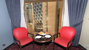 A room with two red chairs around a small table with a fruit bowl. - Carlton Tower Hotel Kuwait (Kuwait City)