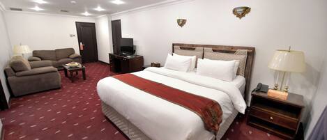 Una habitación de hotel con una cama grande, un sofá, un televisor y un escritorio.