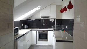 Uma cozinha moderna com forno embutido, cafeteira e utensílios pendurados.