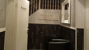 Uma área de recepção com uma placa 'Welcome to CityCentral', um balcão de atendimento e uma lixeira.