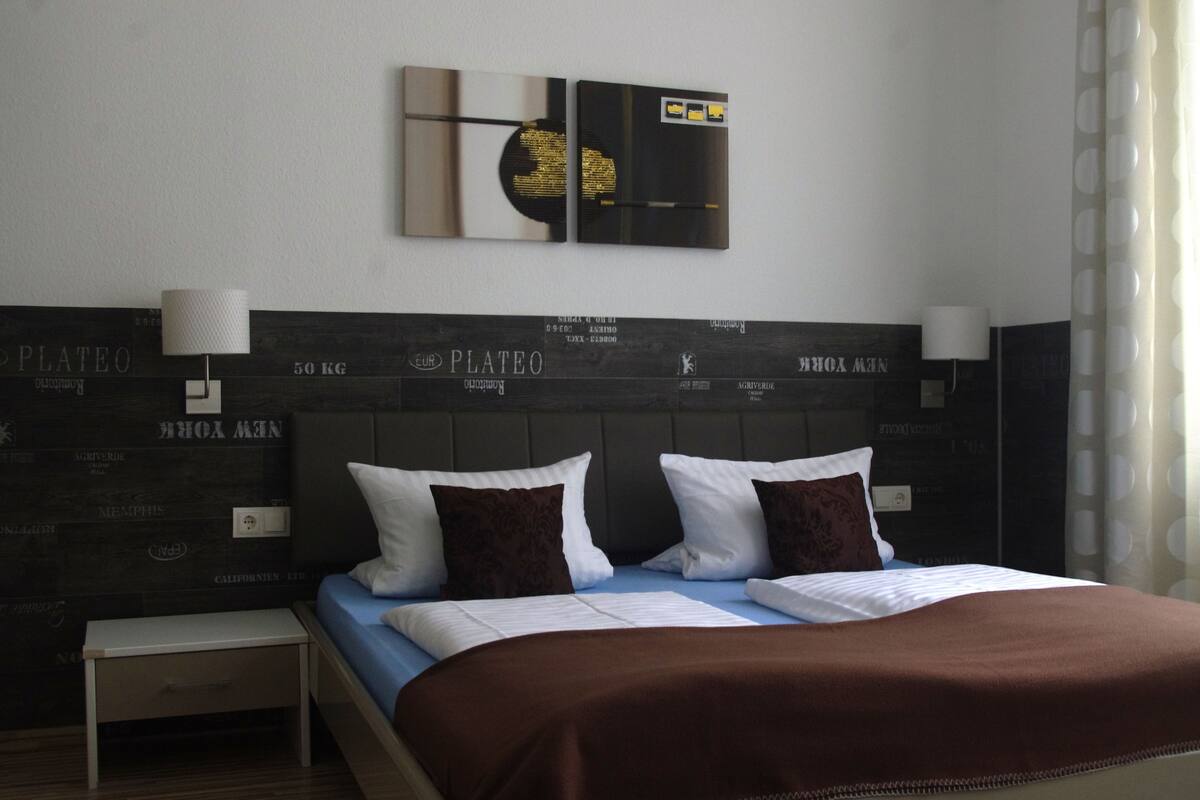 Une chambre d’hôtel avec un lit, une table de chevet et des éléments de décoration murale.