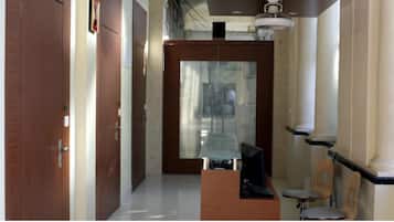 A hallway with a wooden door, a glass partition, and a desk with a computer.
