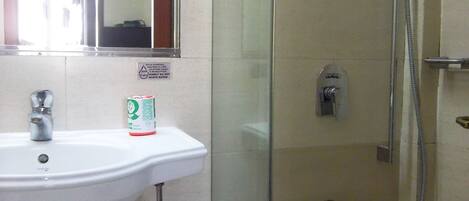 A bathroom with a white sink, a mirror, and a glass-enclosed shower area.