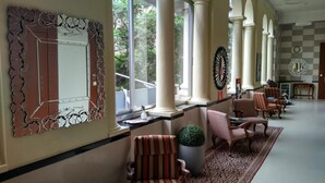 A hotel lobby with a checkered floor, striped chairs, a large mirror, and a potted plant. - Elphinstone Hotel (Mumbai)