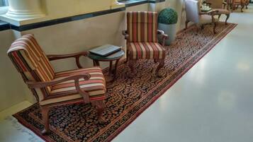 Un vestíbulo con sillones a rayas, una pequeña mesa y una alfombra estampada.