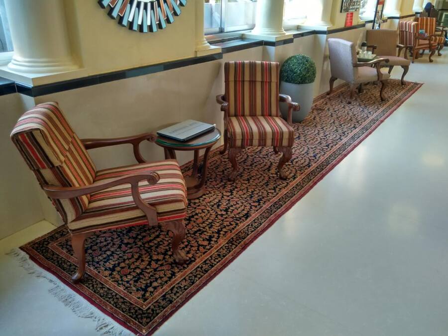 Un vestíbulo con sillones a rayas, una pequeña mesa y una alfombra estampada.