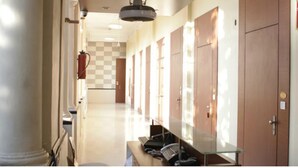 A hotel corridor with a checkered wall, a ceiling fan, and a row of wooden lockers. - Elphinstone Hotel (Mumbai)