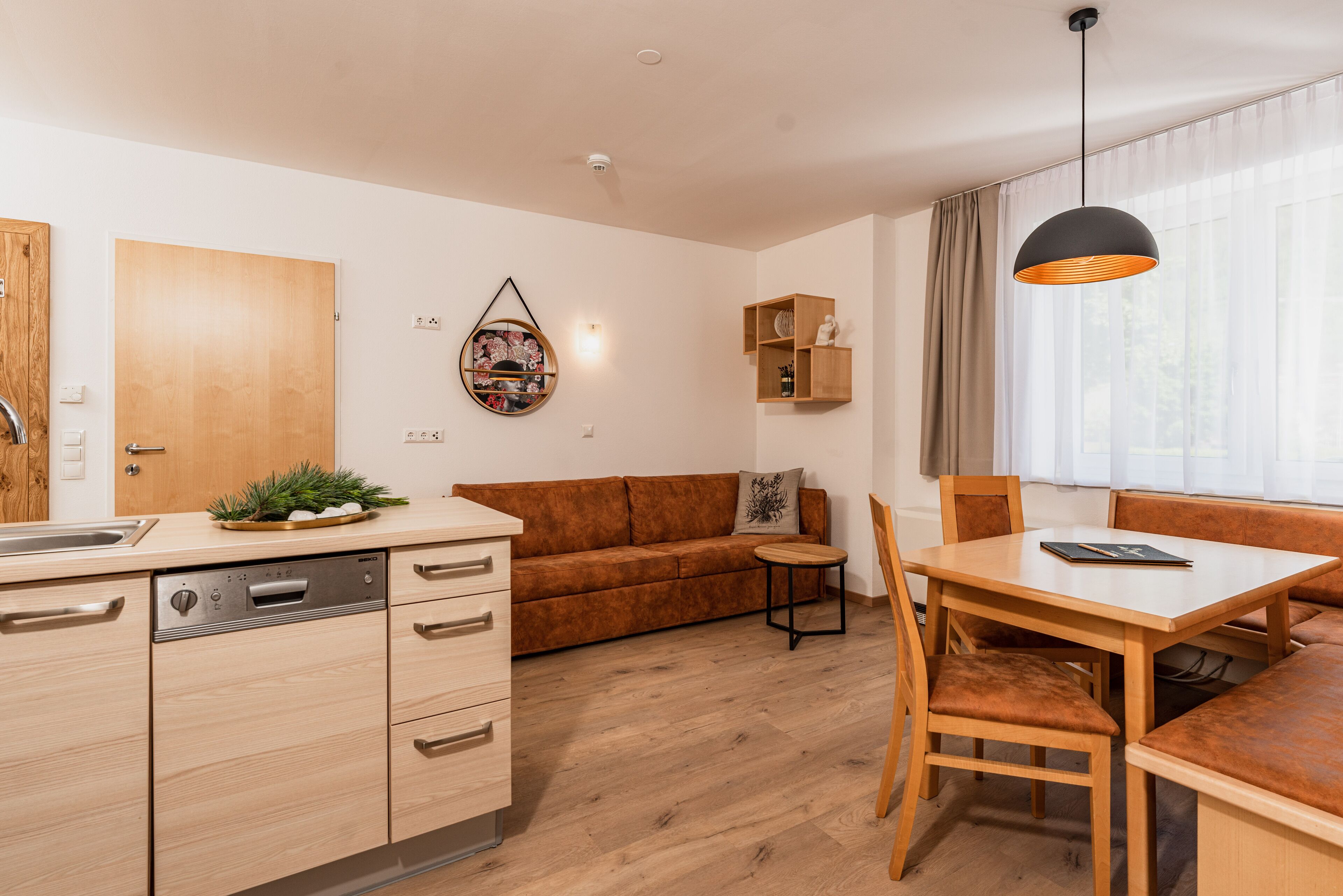 A modern kitchen with wooden cabinets, a dishwasher, and a dining area with a wooden table and chairs.