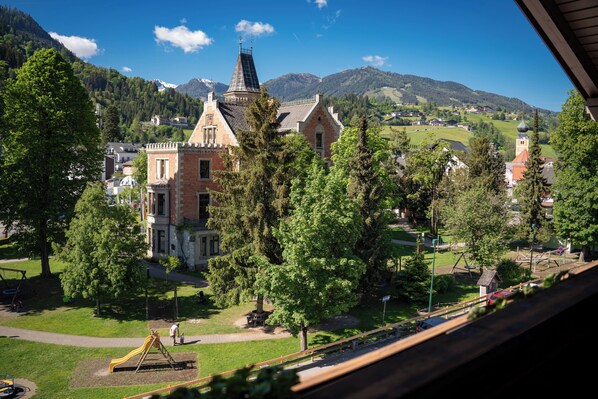 Vista de un pueblo con una iglesia destacada, un parque infantil y zonas verdes circundantes.