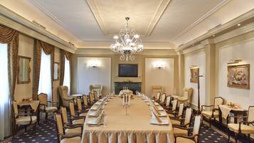 Una sala de reuniones formal con una larga mesa, sillas, un candelabro y luces instaladas en la pared.