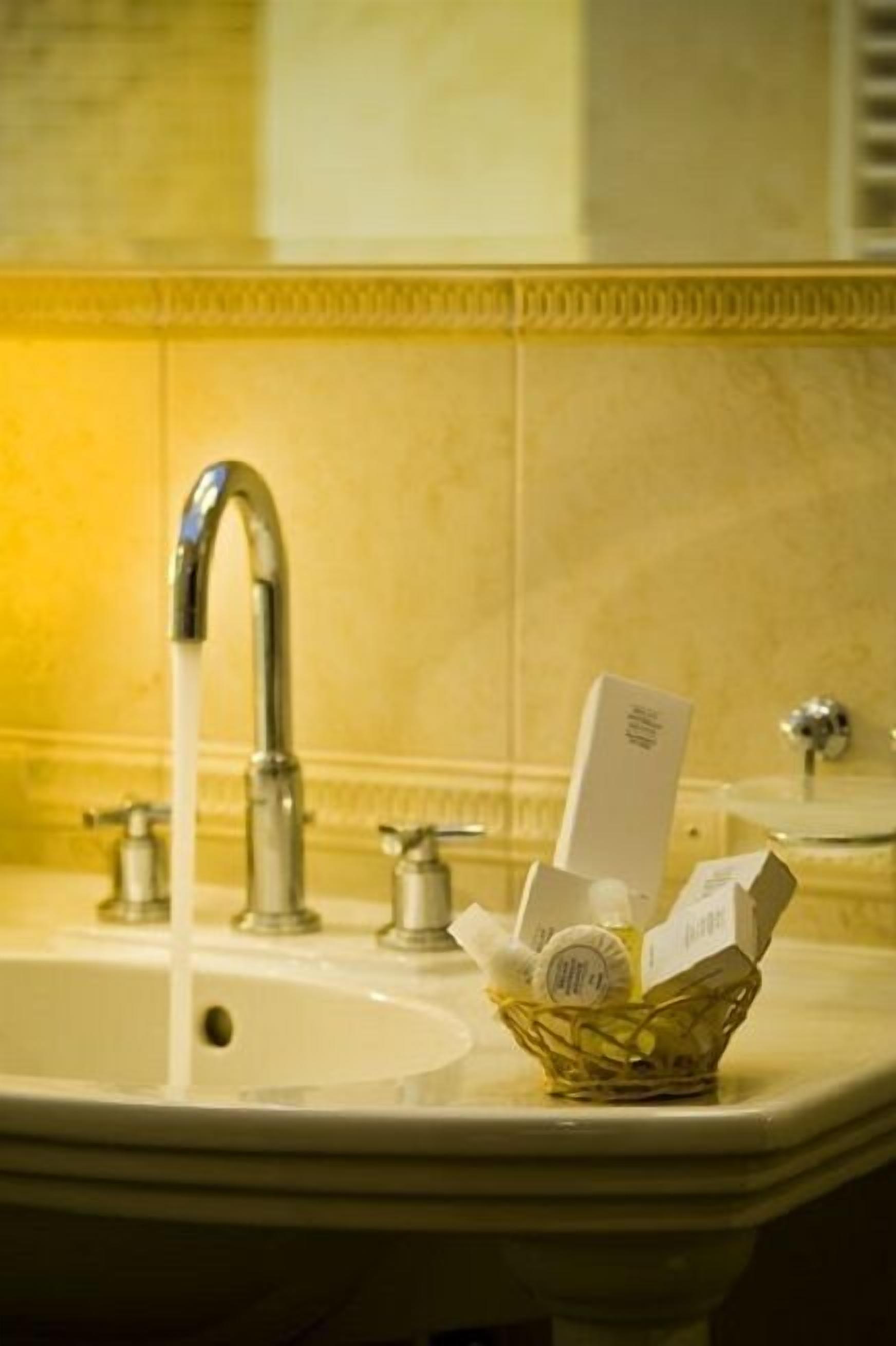 A bathroom sink with running water, a basket of toiletries, and a mirror.