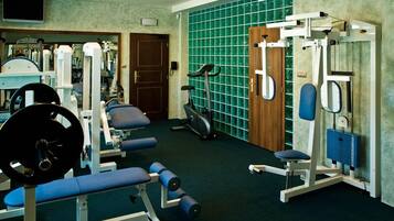 Un gimnasio con varios equipos de ejercicio, incluyendo máquinas de pesas, una caminadora y una bicicleta estática.