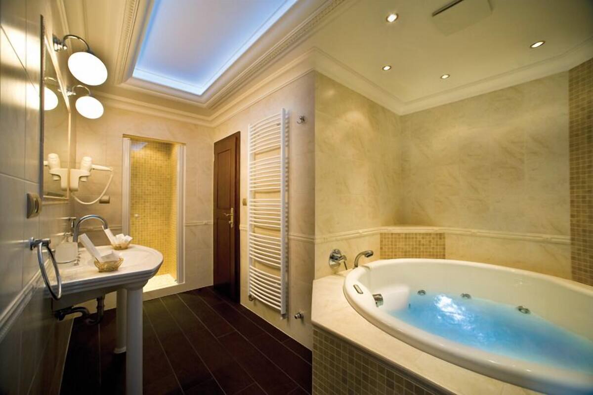 A modern bathroom with a large bathtub, a sink, and a mirror.