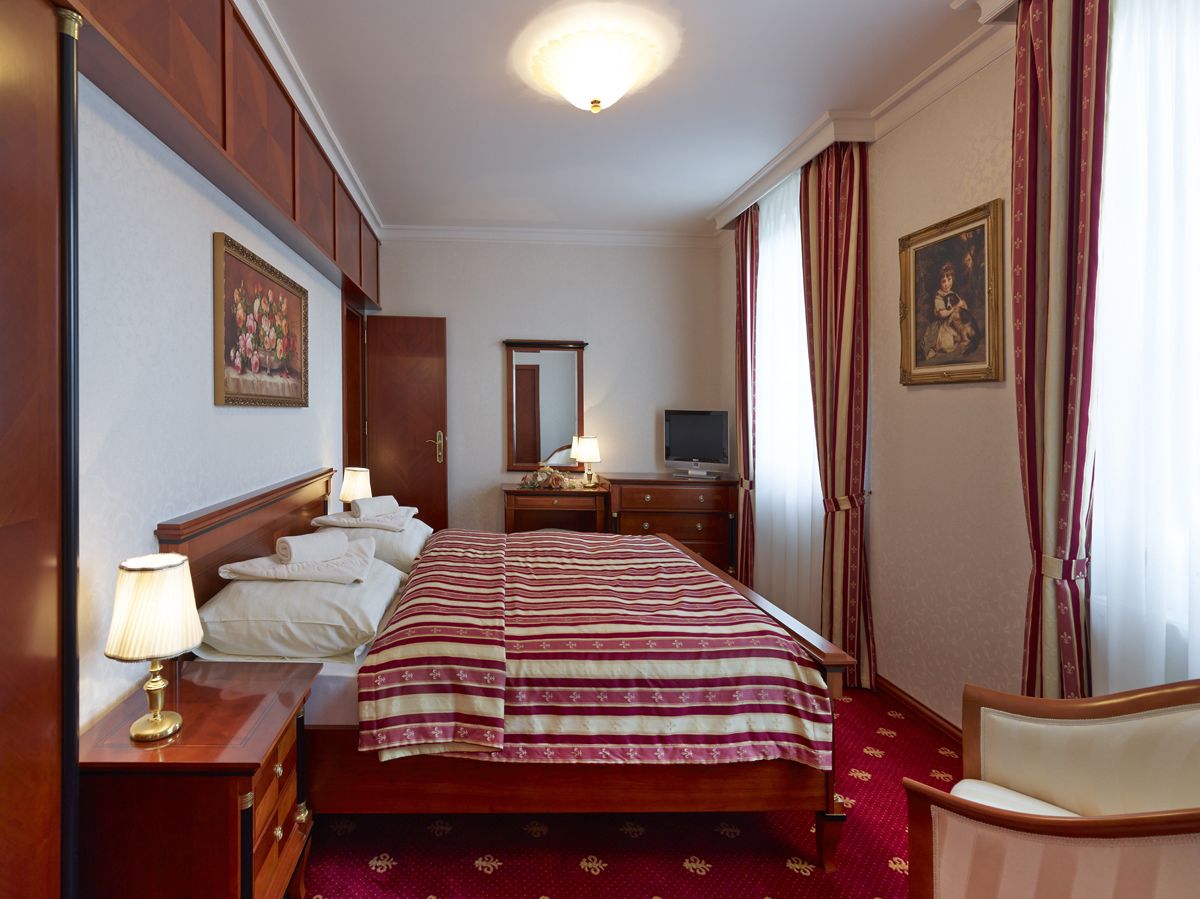 Een hotelkamer met een bed, nachtkastjes, een bureau, een stoel, een televisie en gordijnen.