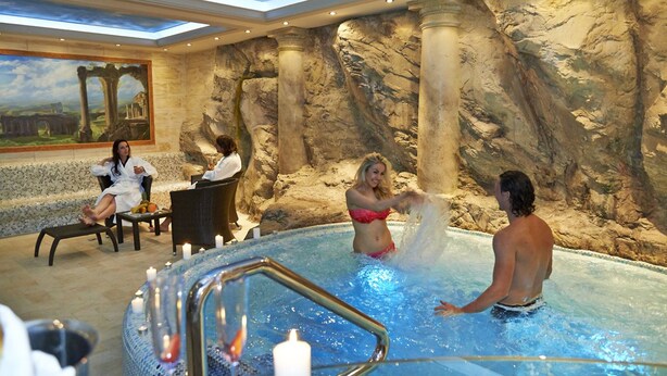 A spa area with a hot tub, seating, and a mural of ruins.