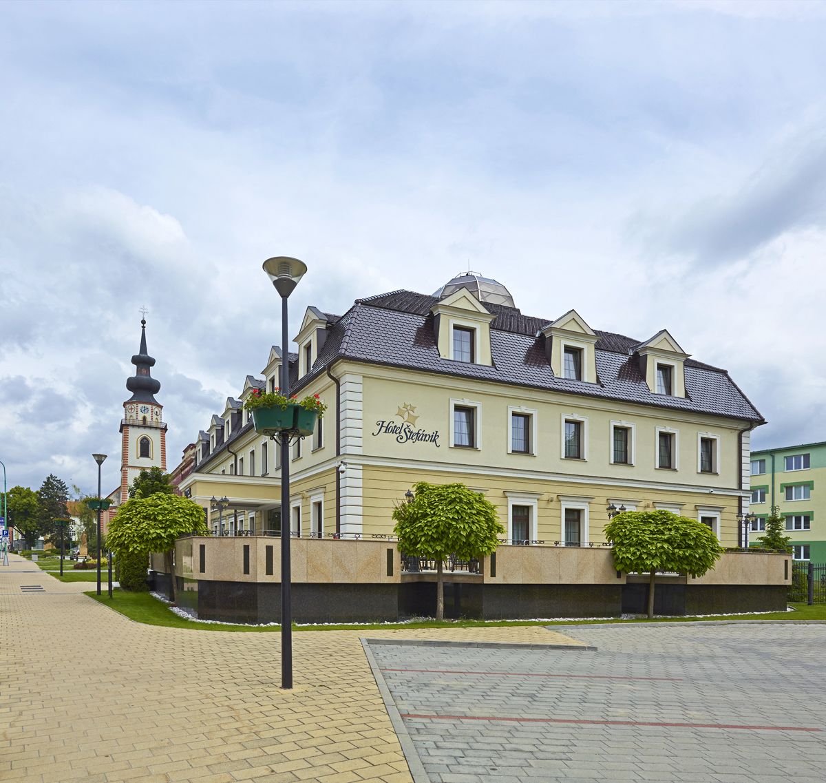 Un edificio histórico con una torre de reloj, con la leyenda “Hotel Siedlarski”, que presenta un estilo arquitectónico europeo clásico con ventanas simétricas y un techo de tejas.