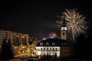 A building with a clock tower and a dome, surrounded by urban buildings and a street with cars.