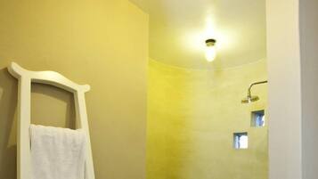 Un baño con ducha, un toallero blanco y una lámpara.