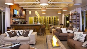 Un espace de détente moderne comprenant des canapés, un foyer et un bar avec un comptoir en bois.
