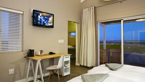 Une chambre d’hôtel avec un lit, un bureau et une chaise, un téléviseur fixé au mur et une vue sur l’extérieur grâce à une grande fenêtre.