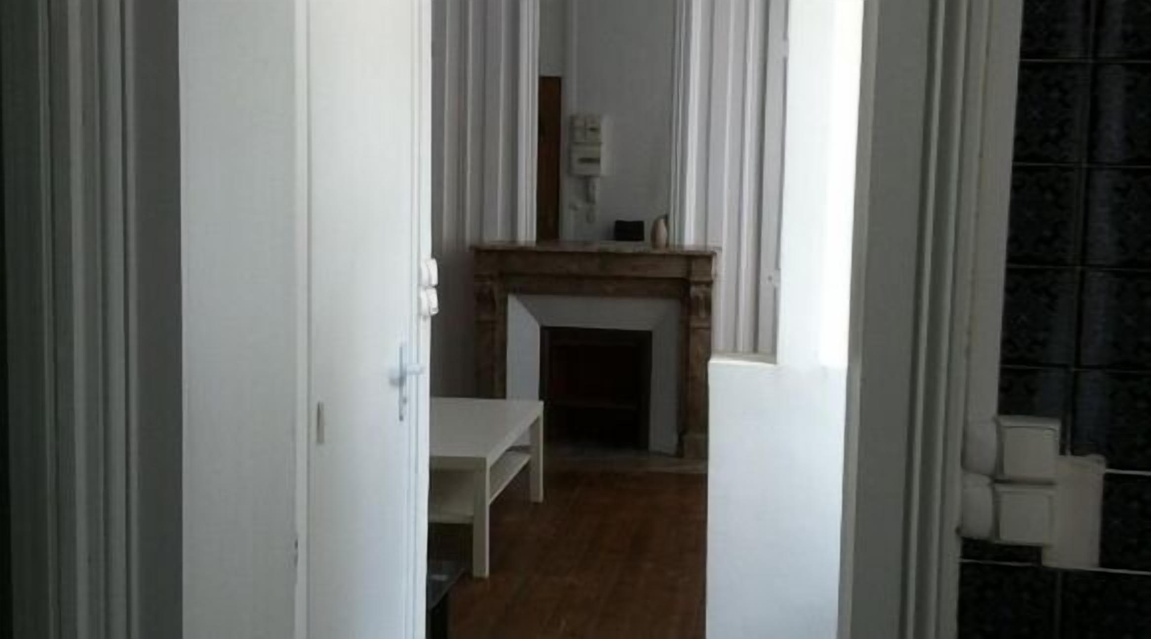 Un pasillo estrecho con suelo de madera que conduce a una habitación con chimenea.