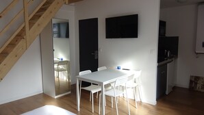 A compact kitchen with a dining area, wooden staircase, and a small living space. - Nationale AppartHotel (Lille)