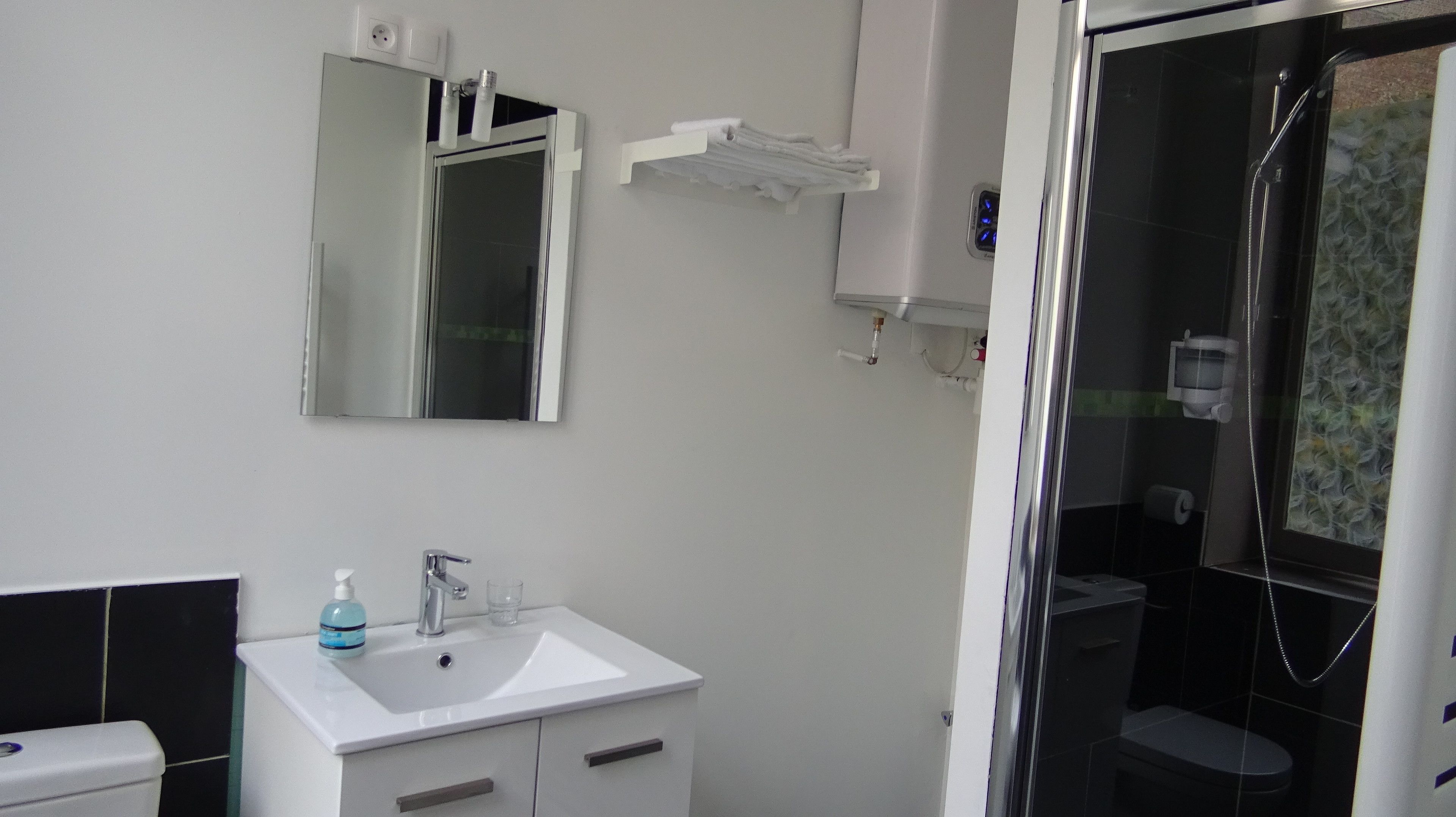 A bathroom with a white sink, mirror, and a glass shower enclosure.