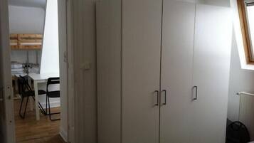 Una habitación con un armario grande, una mesa de comedor con sillas y un radiador.