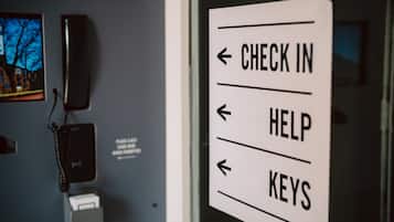 Schild mit Pfeilen, die zu 'CHECK IN', 'HELP' und 'KEYS' weisen und Gästen den Weg zeigen.