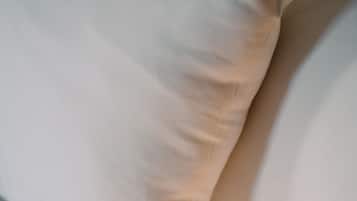 Primer plano de un almohadón blanco sobre una cama con textura suave.