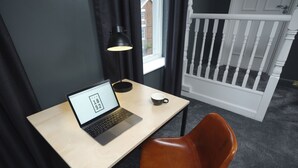 Un espacio de trabajo pequeño y ordenado con una computadora portátil, una taza y una lámpara.