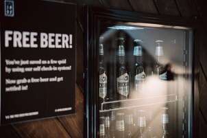 A freezer with bottles of beer and a sign offering free beer.