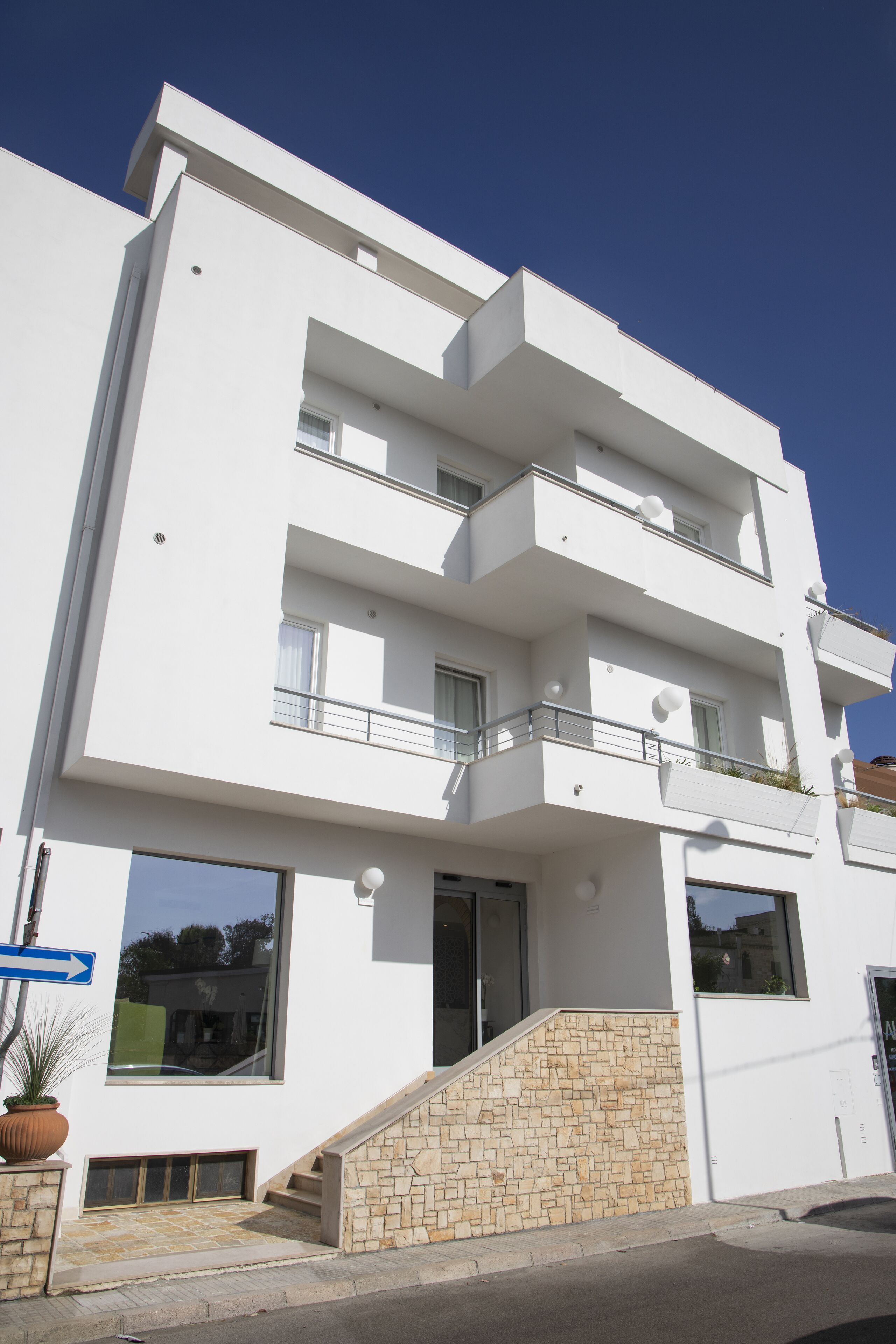Un edificio moderno de varios pisos con techo plano, ventanas amplias y entrada de piedra.