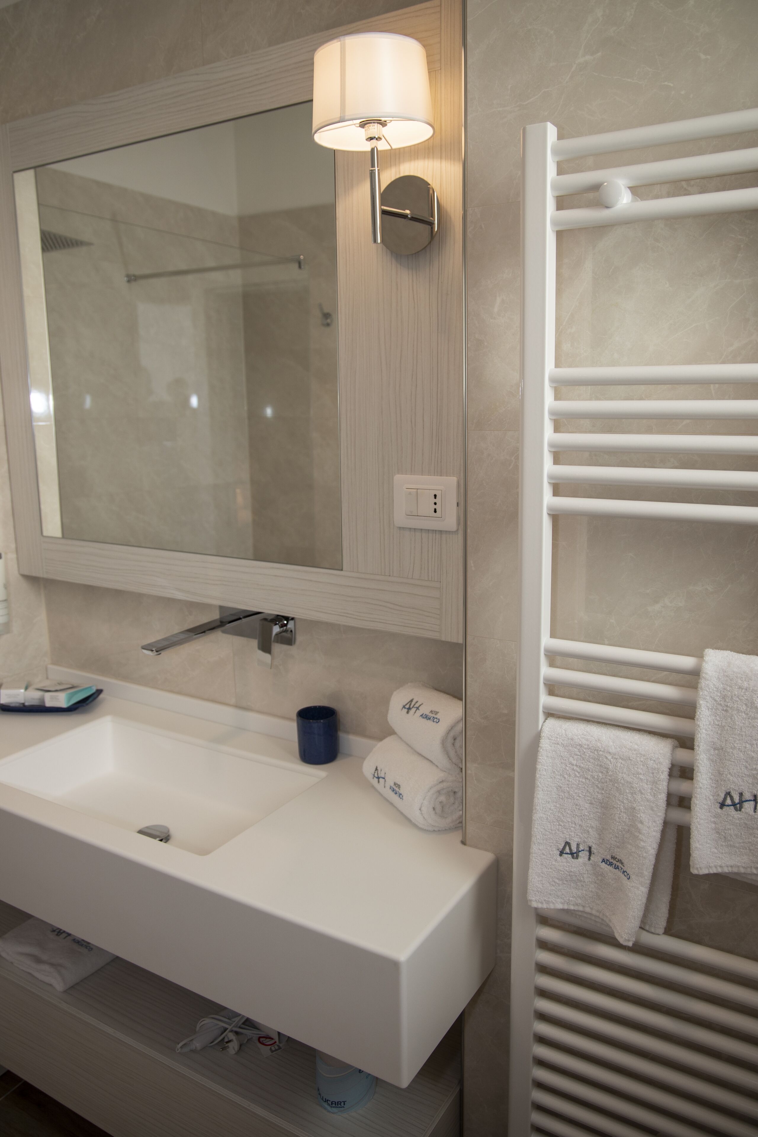 Un baño moderno con un espejo grande, lavamanos blanco y barra para toallas.