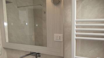 Un baño moderno con un espejo grande, lavamanos blanco y barra para toallas.